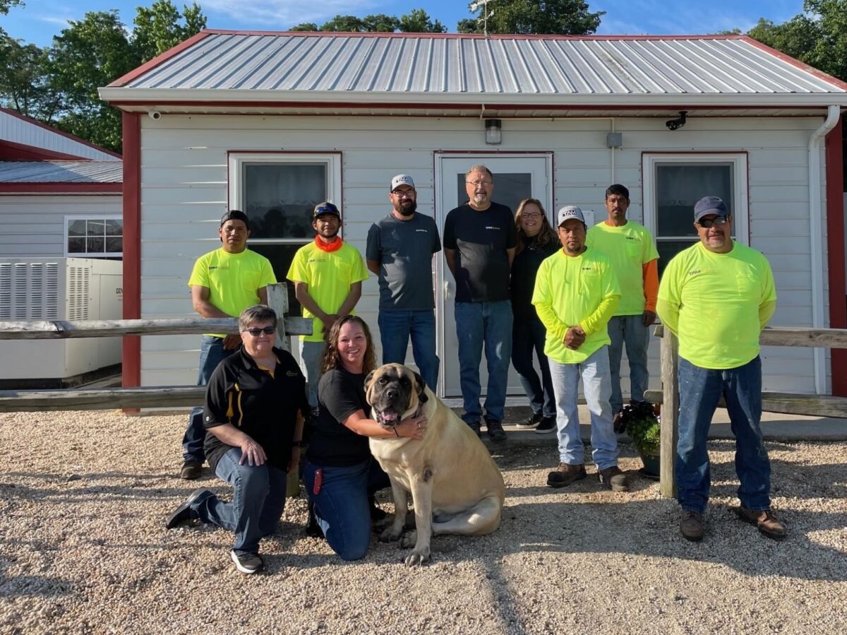 Westwood team and dog on farm in front of building